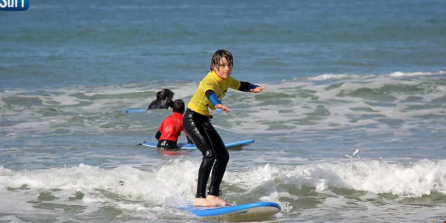 Une jeune surfeuse se relève sur sa planche dans l'écume