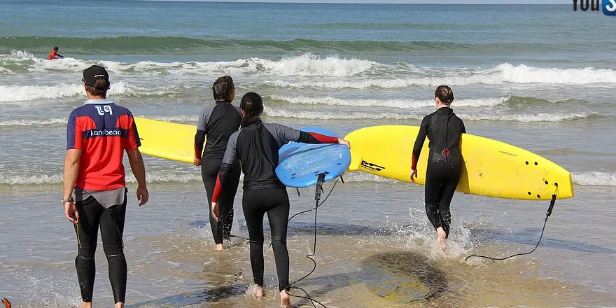 Élèves entrant dans l'eau avec leurs planches